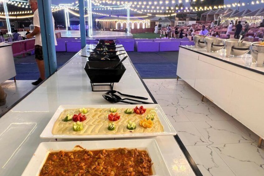 A buffet with various dishes, including a pasta dish with vegetables and a meat-based dish. 4