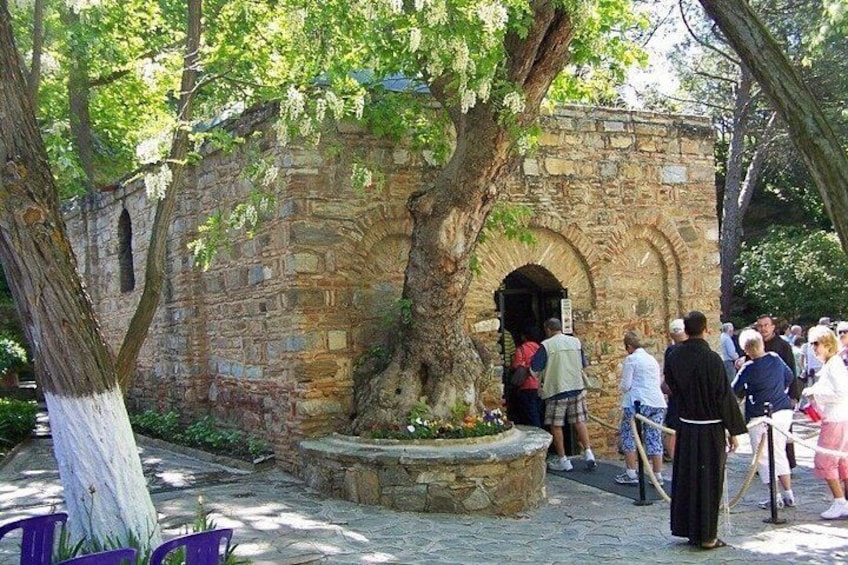 A stone building with an arched entrance, surrounded by trees and a stone bench. 4