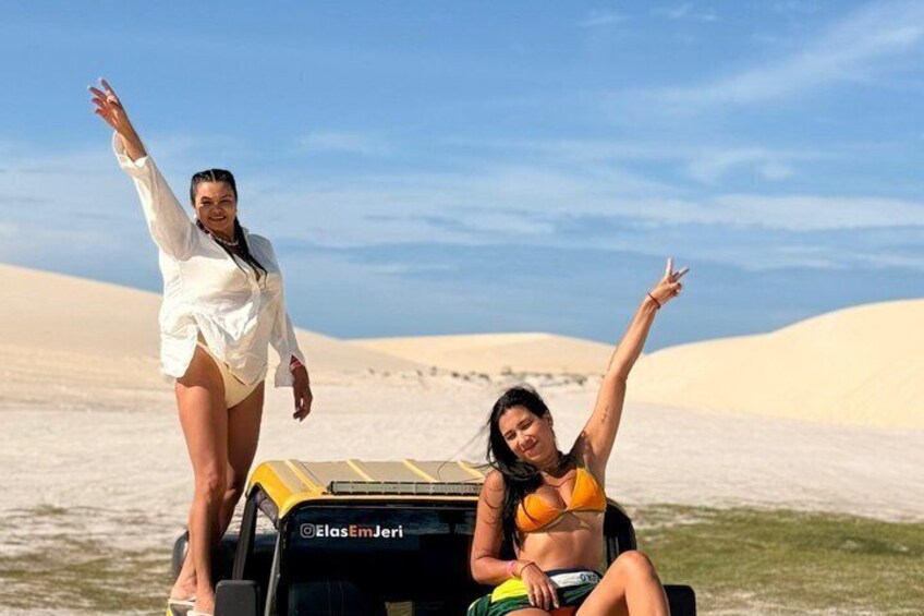 Two people in a desert landscape with sand dunes in the background. 3