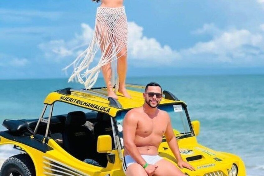 A yellow vehicle with a person standing on top and another sitting in front. 4