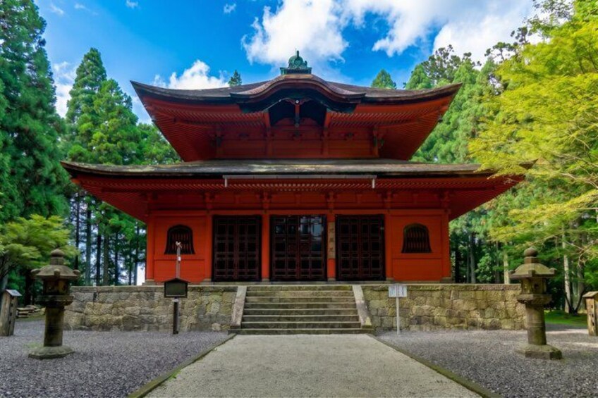 A traditional Japanese temple with a red roof, stone lanterns, and a gravel pathway. 3