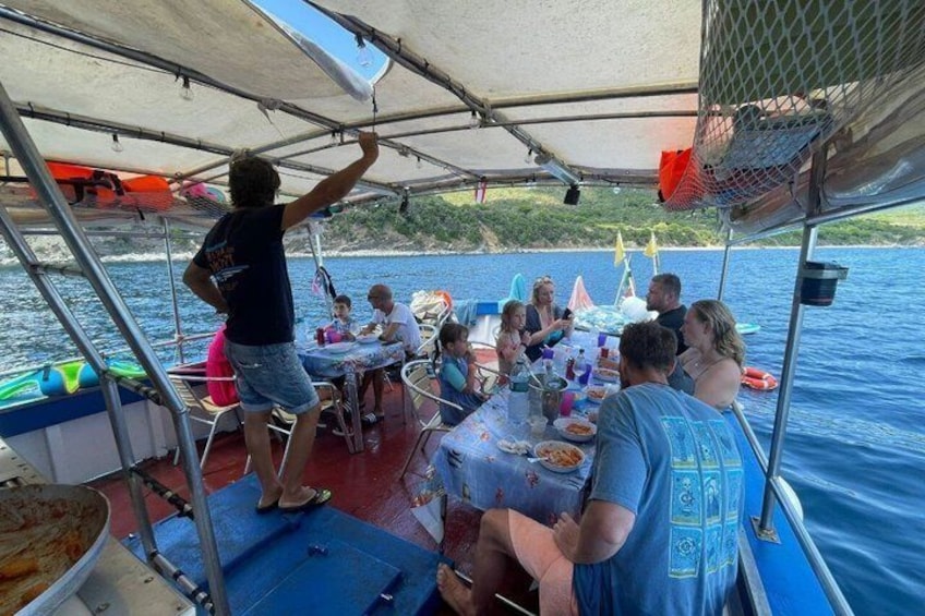A group of people on a boat with a table set up under a canopy, surrounded by water. 1