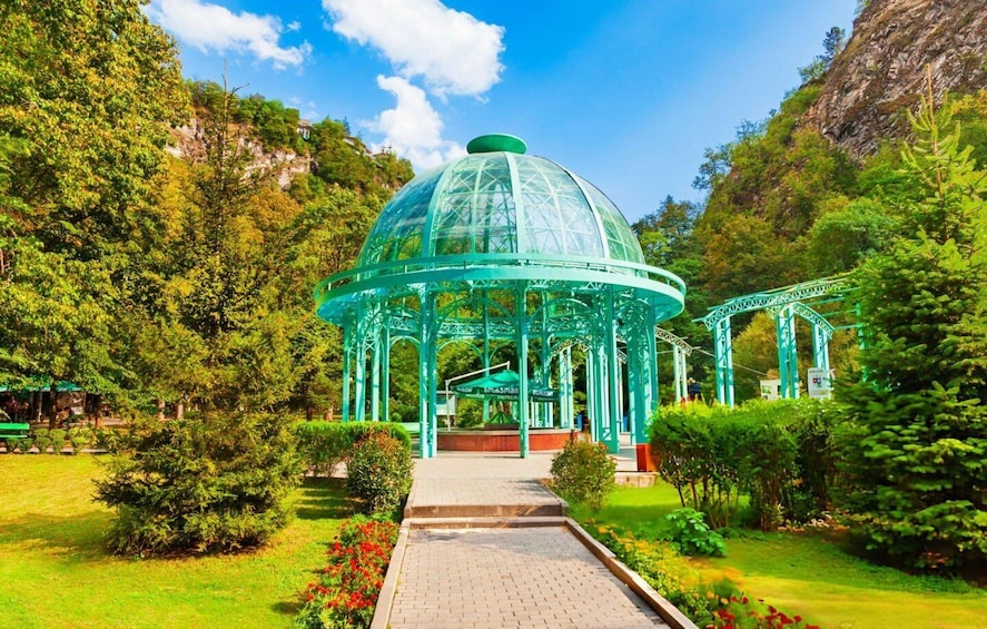 A glass-domed pavilion surrounded by lush greenery and a clear blue sky. 4