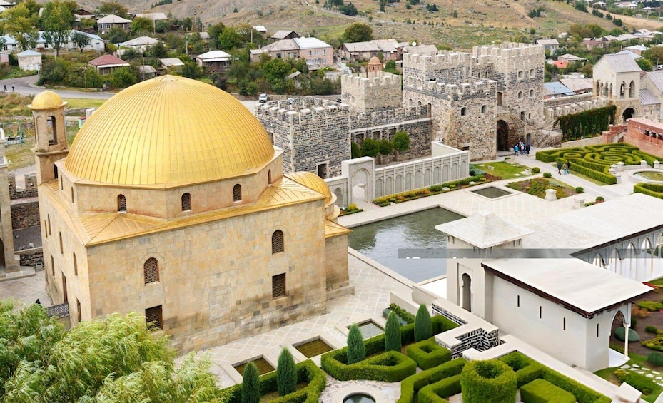 A historic cityscape with a prominent golden-domed building, a fortified castle, and a river. 5