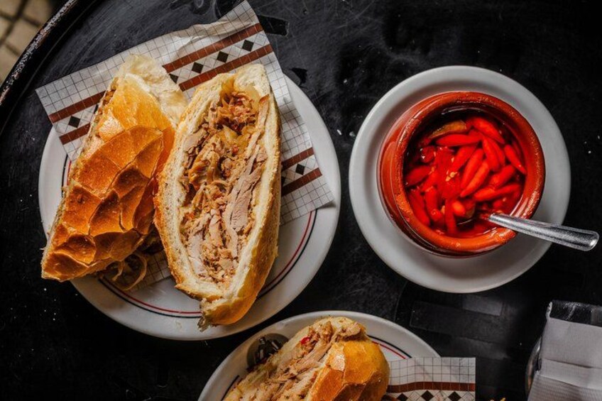 A sandwich on a plate, a bowl of red peppers, and a napkin on a table. 1