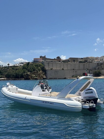 Een witte motorboot genaamd ICON 285 afgemeerd nabij een kustfort. 1