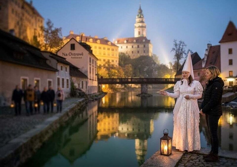 A couple in traditional attire by a river with a castle in the background. 5