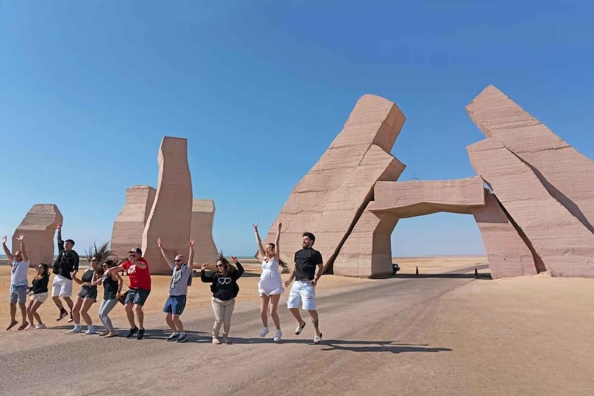 A group of people dancing in a desert with large rock formations in the background. 1