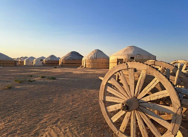 A desert landscape with yurts and a wooden cart. 5