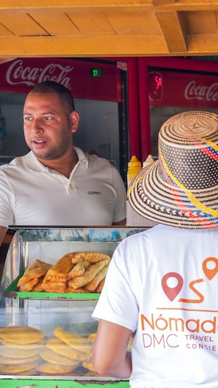 A food vendor with a display of fried pastries, a Coca-Cola sign, and a travel agency logo. 2