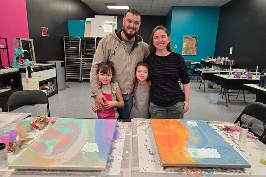 A family at an art workshop with painting supplies and canvases. 2