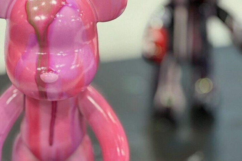 Un oggetto rosa con una superficie lucida, forse un giocattolo o una statuina, su una superficie riflettente. 2