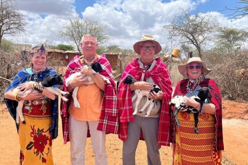 Quatre personnes, vêtues de costumes traditionnels, tiennent des chiens dans un paysage désertique où la végétation est rare. 2