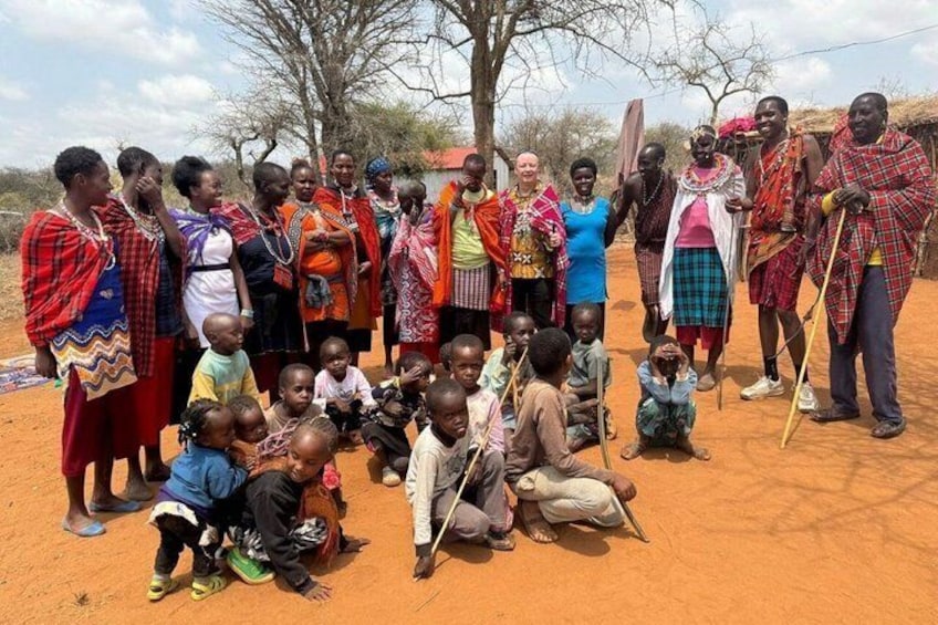 Un groupe de personnes, vêtues de costumes traditionnels, s’est rassemblé dans un environnement aride, évoquant un désert, où la végétation est rare. 3
