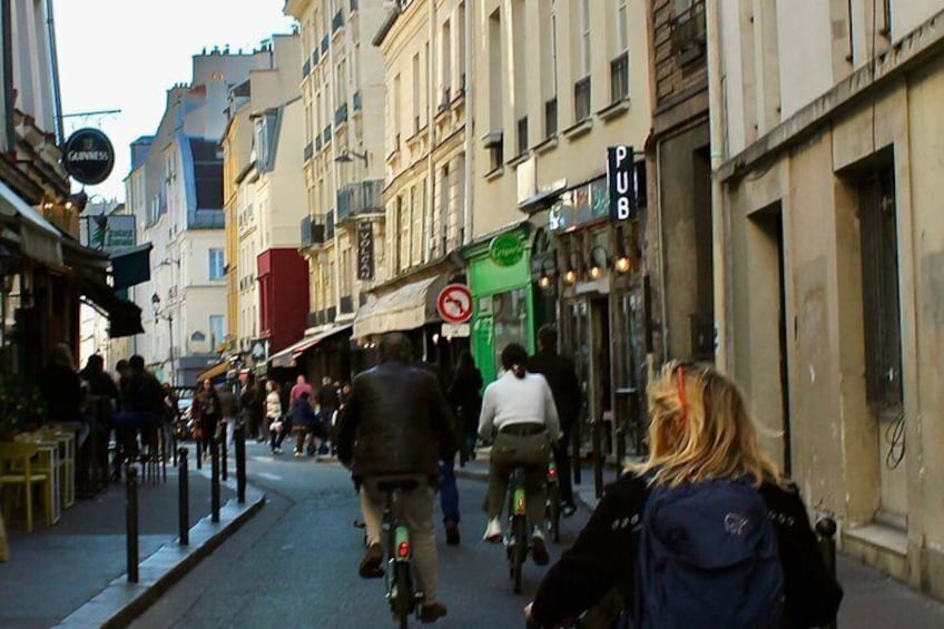 A busy urban street with pedestrians, cyclists, and storefronts. 4