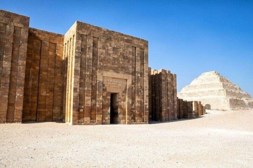 En stor bygning i sten med en pyramide i baggrunden. 3