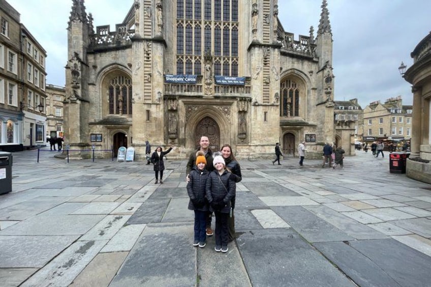 A historic building with Gothic architecture, a large open square, and people walking around. 4
