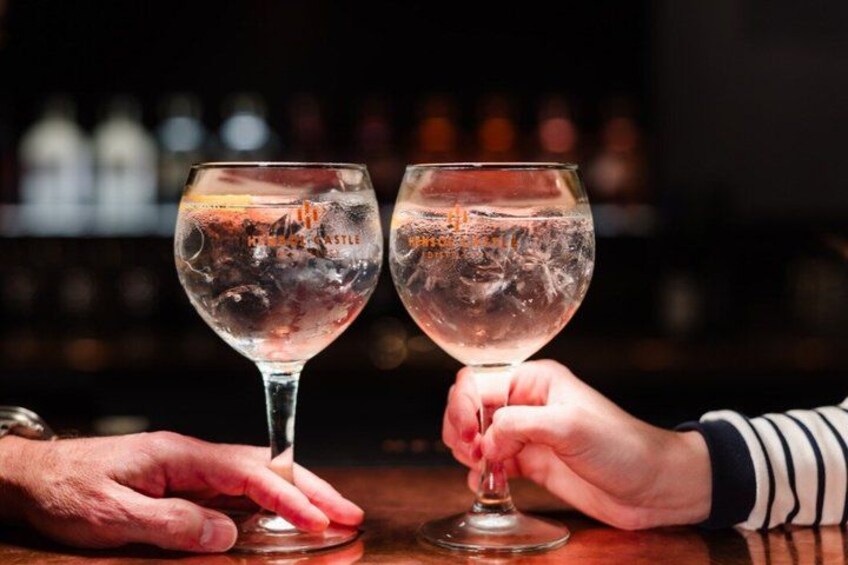 Twee handen die wijnglazen met ijsblokjes vasthouden, met een bar op de achtergrond. 2