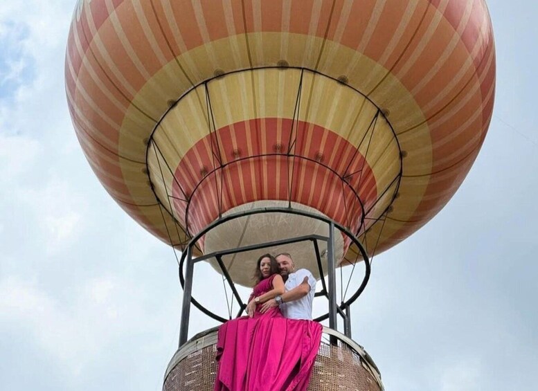 A hot air balloon with a striped canopy, a wicker basket, and a person in a pink dress. 4