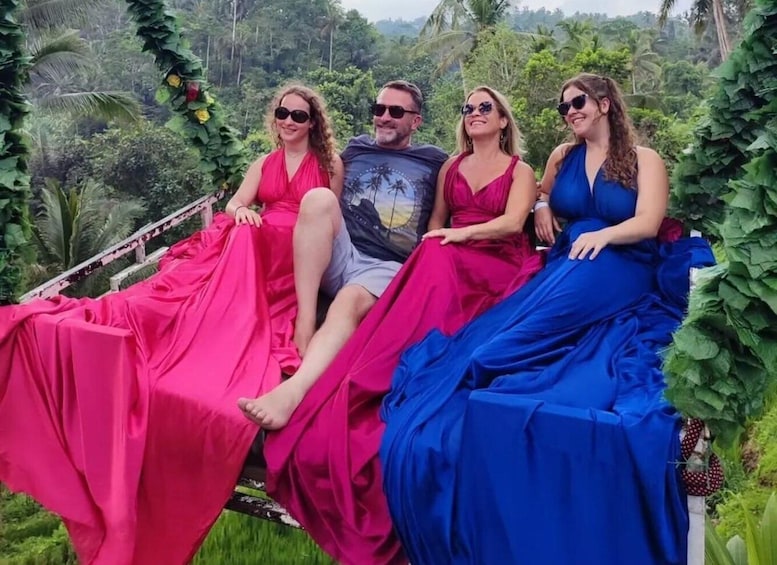 Four people sitting on a wooden bench surrounded by lush greenery. 5