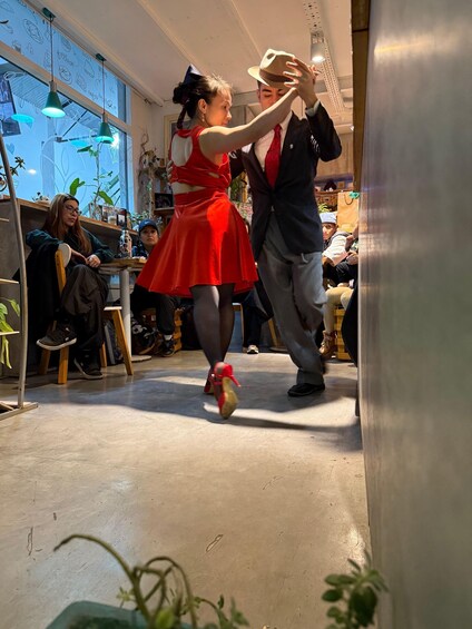 A couple dancing in a room with wooden floors and shelves filled with items. 5
