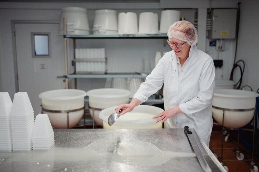 A person in a white lab coat working with a large mixing bowl in a kitchen setting. 5