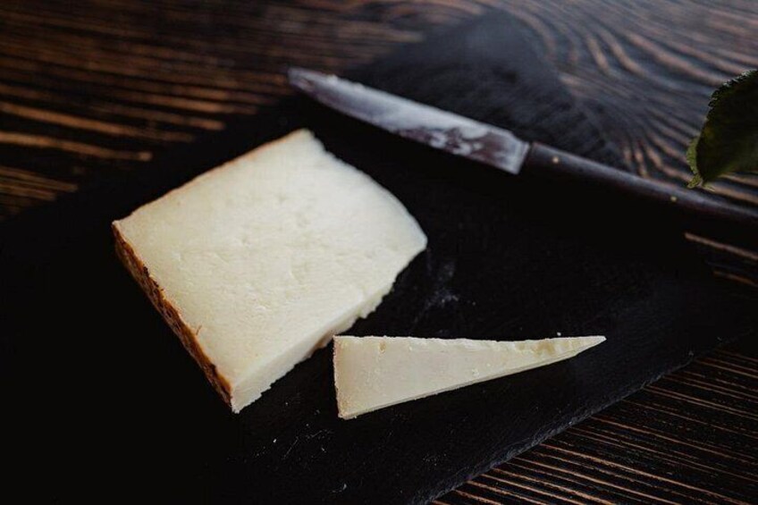 A piece of white cheese on a black cutting board with a knife beside it. 2