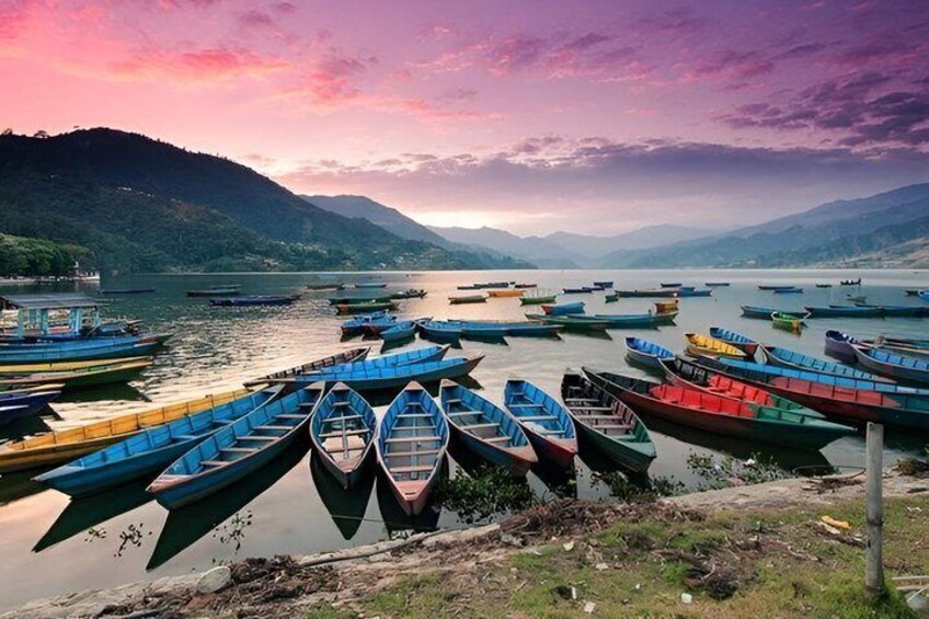 A lakeside with colorful boats docked along the shore and mountains in the background. 2