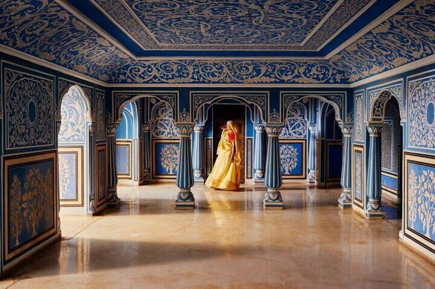 An ornate hallway with blue and gold decorations, featuring a woman in a yellow dress. 4
