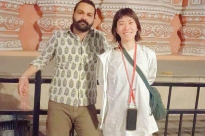 Two people standing in front of a patterned wall. 2