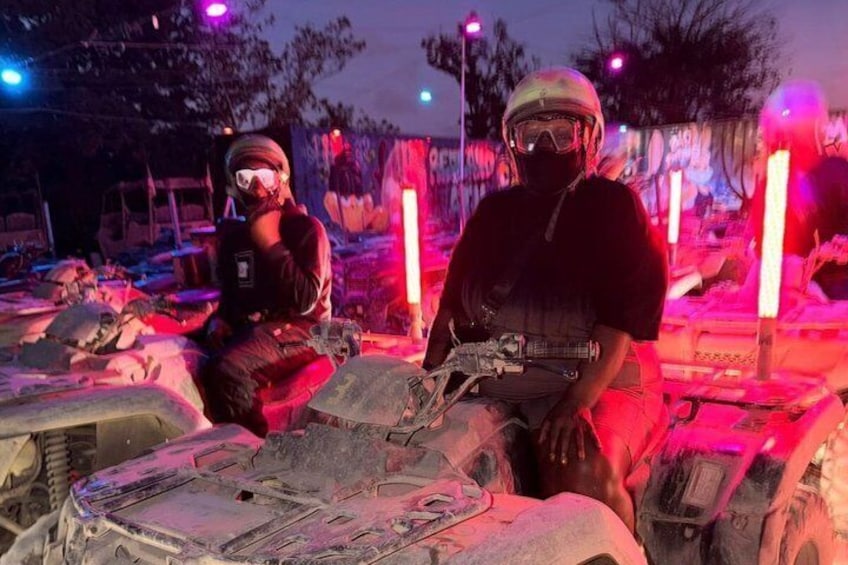 Two individuals on ATVs in a nighttime setting with red lighting. 1