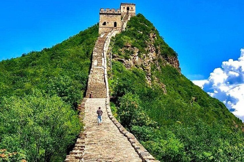 Una persona che cammina sulla Grande Muraglia cinese, circondata da colline verdeggianti. 5