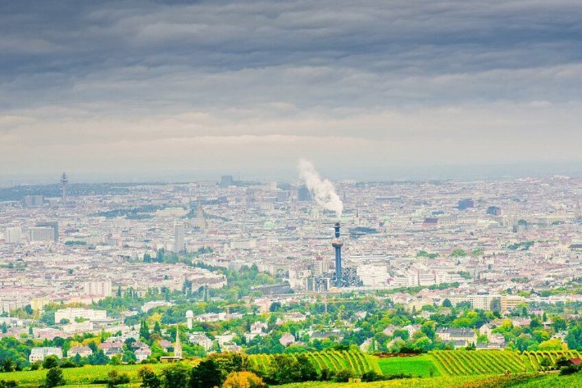 Un paisaje urbano con una torre destacada que emite humo, rodeado de edificios y zonas verdes. 2