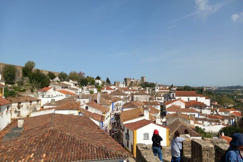Un pueblo histórico con edificios de tejados de terracota, una iglesia destacada y un castillo al fondo. 5