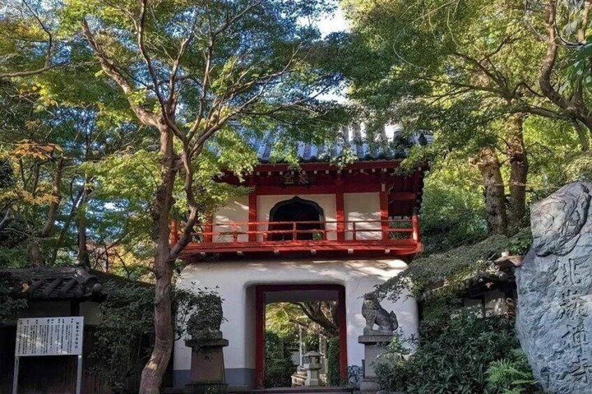 A traditional Japanese gate with red and white colors, surrounded by lush greenery and trees. 2