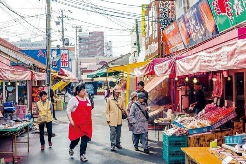 A busy street market with various stalls and people shopping. 4