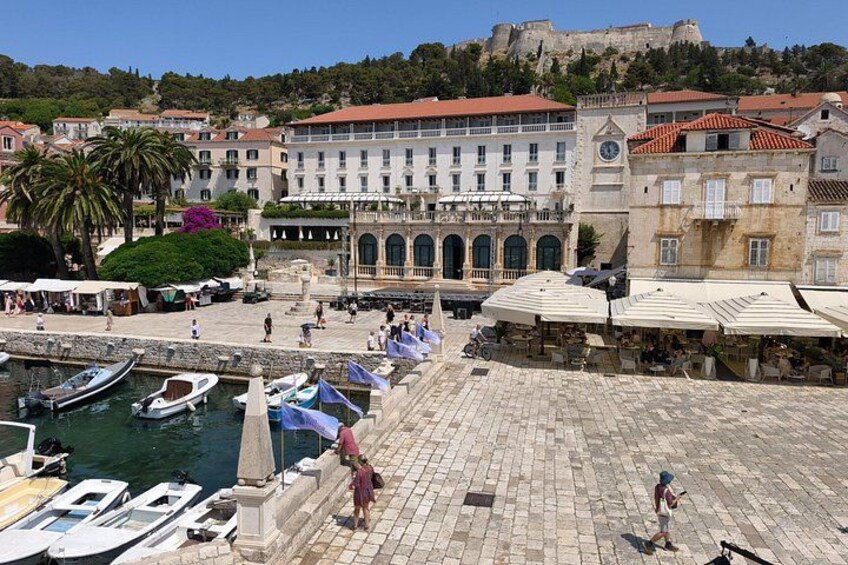A harbor with boats, a historic building, and a fort on a hill. 3