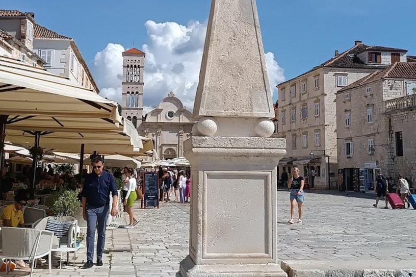 A cobblestone square with a central obelisk, outdoor cafes, and historic buildings. 5