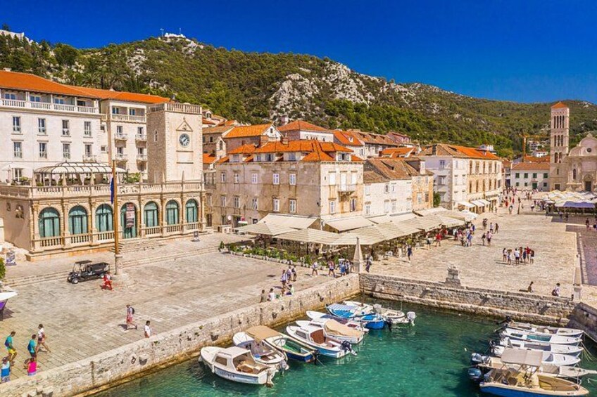 Una cittadina costiera con edifici storici, un porto con barche e montagne sullo sfondo. 3