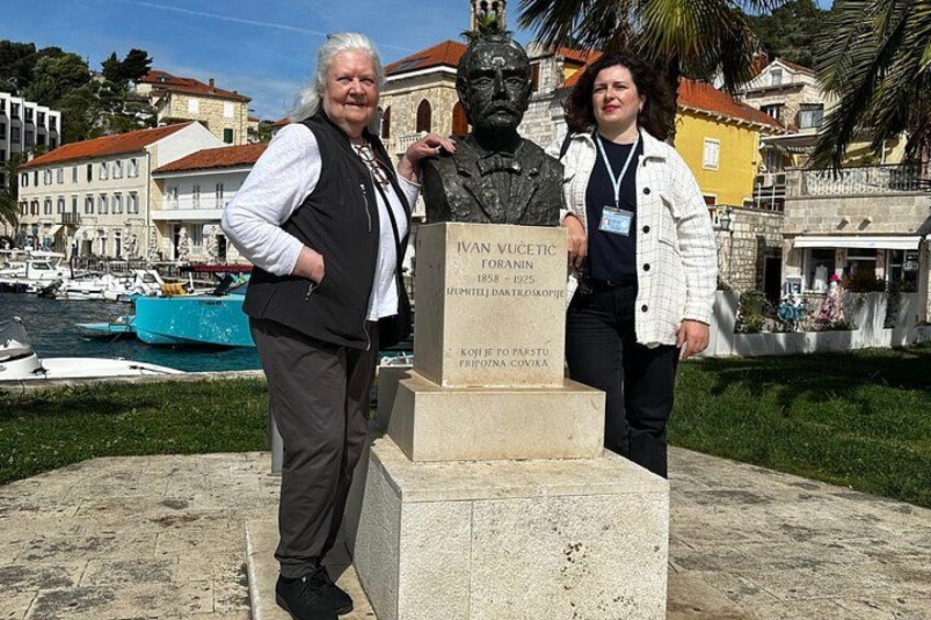 Una statua di Van Vucetic in una piazza pubblica, con uno specchio d'acqua e edifici sullo sfondo. 2