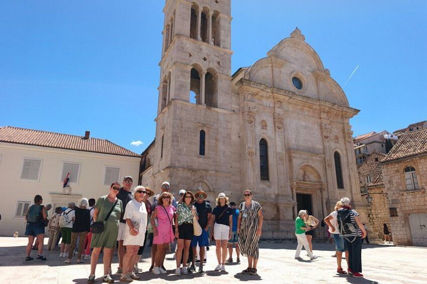 Un gruppo di persone in piedi di fronte a una chiesa storica con un campanile. 5
