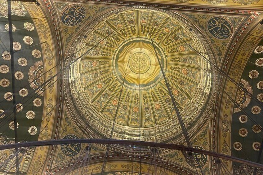 Eine detailreiche Decke mit einem zentralen, kreisförmigen Design, umgeben von aufwendigen Mustern und Ornamenten. 3
