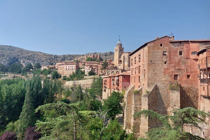 Un pueblo histórico con edificios de piedra, una iglesia destacada y una fortaleza en la cima de una colina. 3