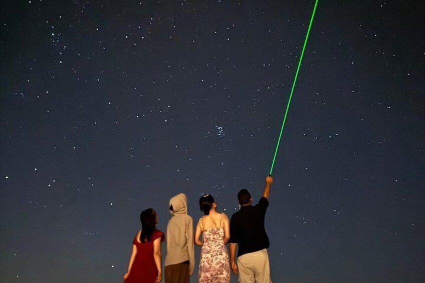 Un grupo de personas mirando las estrellas con un puntero láser verde. 2