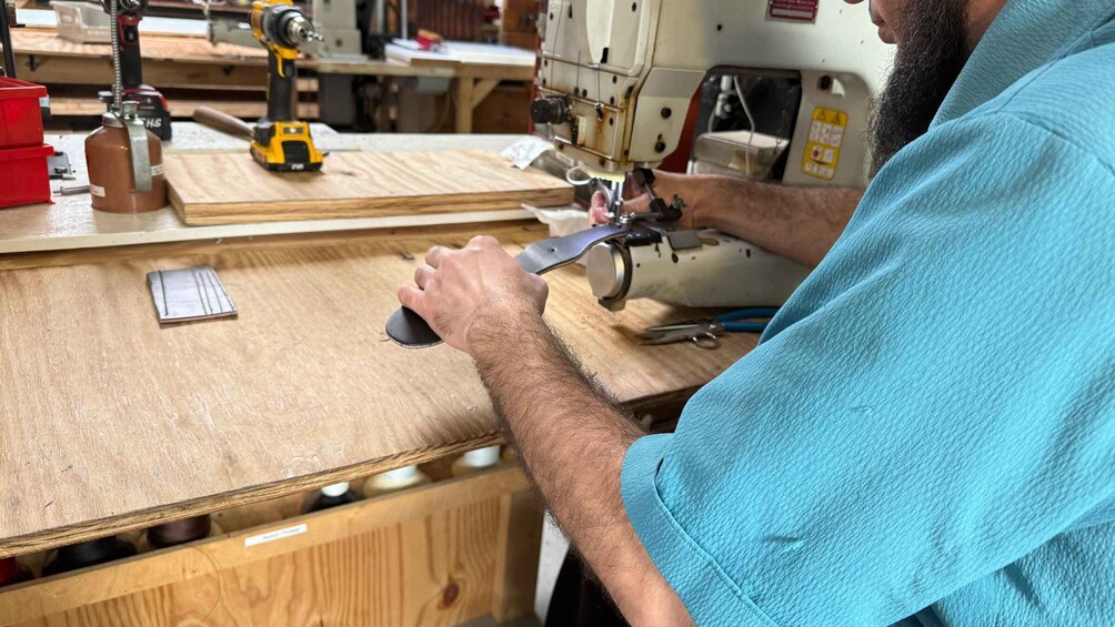 A person working with a sewing machine on a wooden surface, surrounded by tools and materials. 3