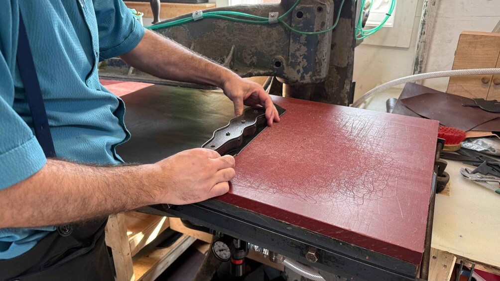 A person using a metal tool on a red wooden surface. 1