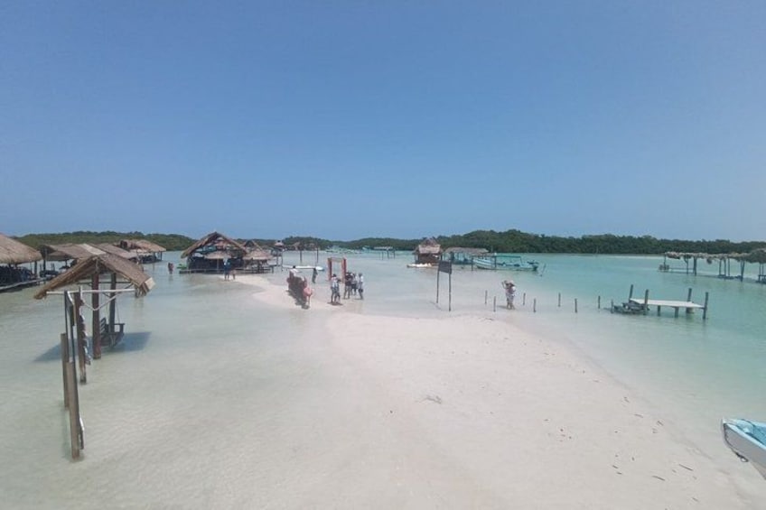 Una playa con bungalows sobre el agua, agua turquesa cristalina y una orilla arenosa. 3