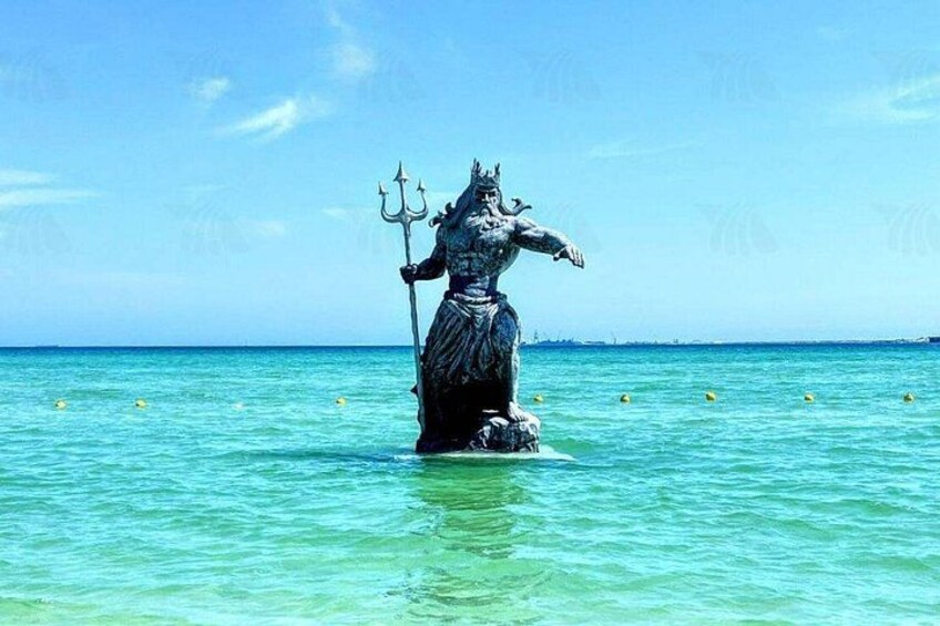 Eine Statue einer mythologischen Figur steht in klarem, türkisblauem Wasser. 1