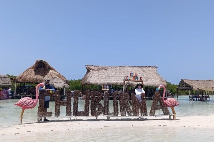 Una playa con cabañas de techo de paja y un cartel que dice 'Fiji'. 5