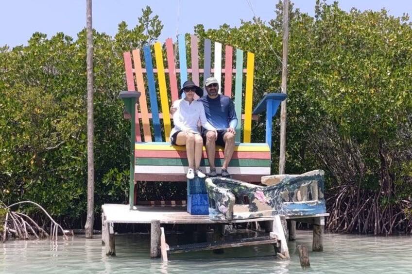 Dos personas sentadas en un banco colorido en una zona de manglares. 2